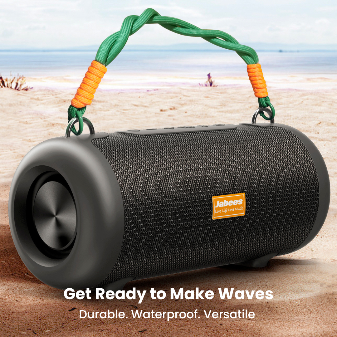 Black portable speaker with green and orange handle on a beach
