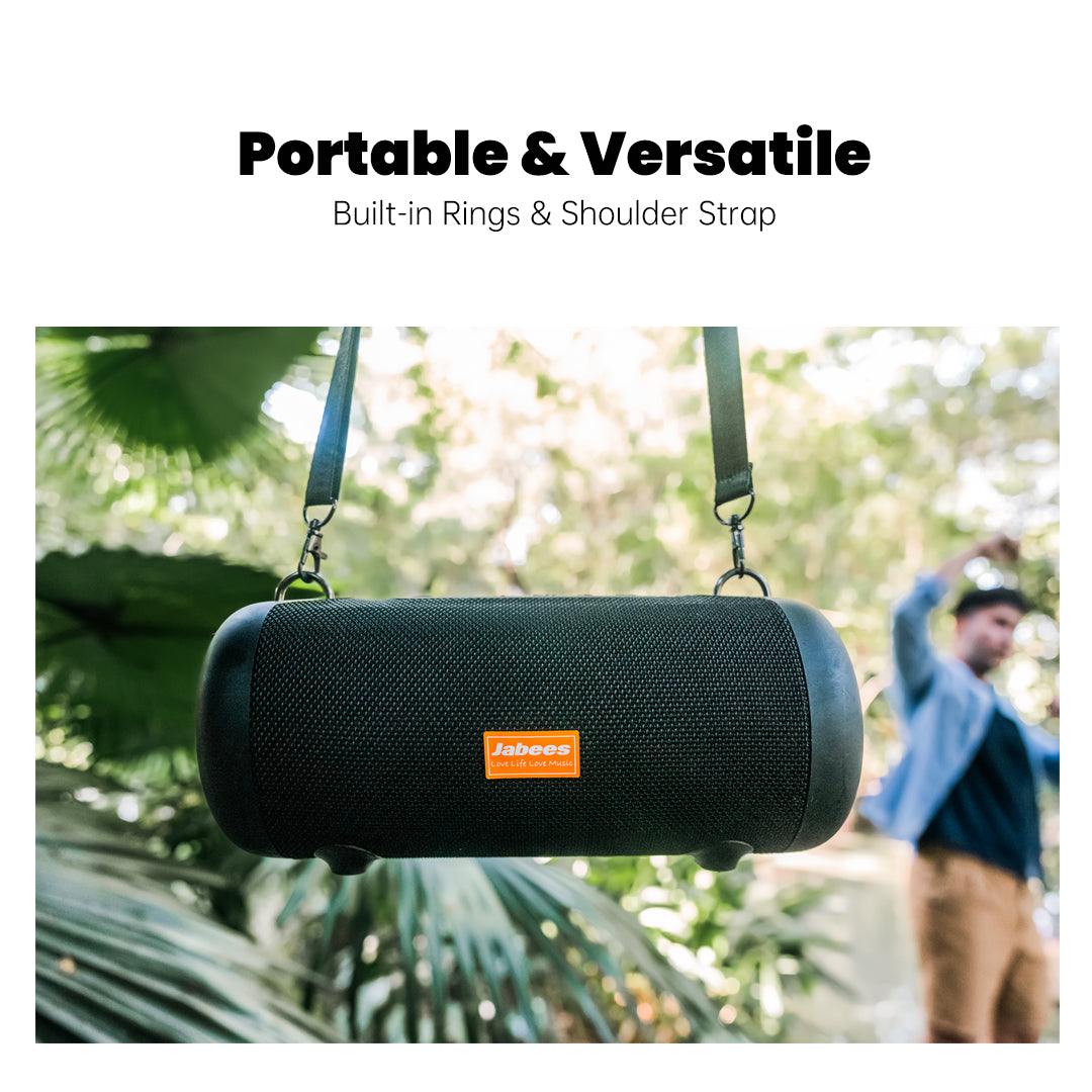 Black portable speaker with a built-in ring and shoulder strap, hanging outdoors.